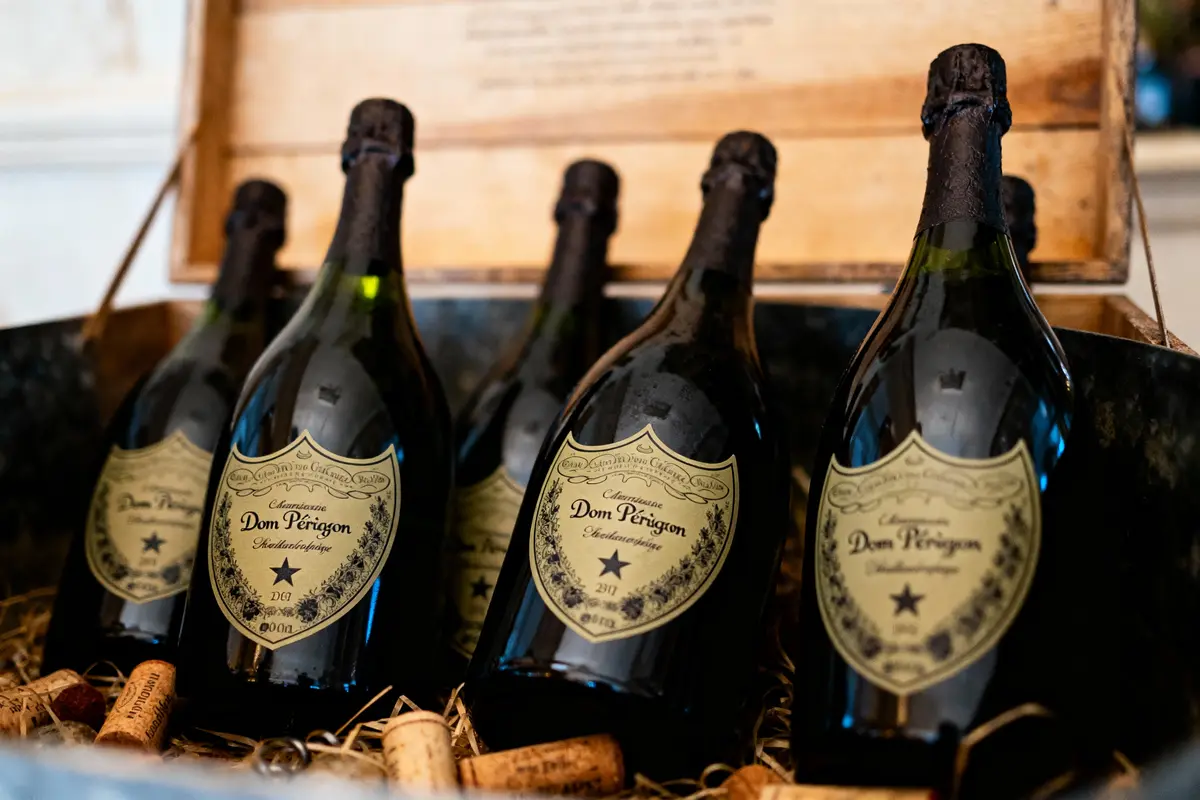 Cinq bouteilles de champagne Dom Pérignon dans une boîte en bois, entourées de bouchons.