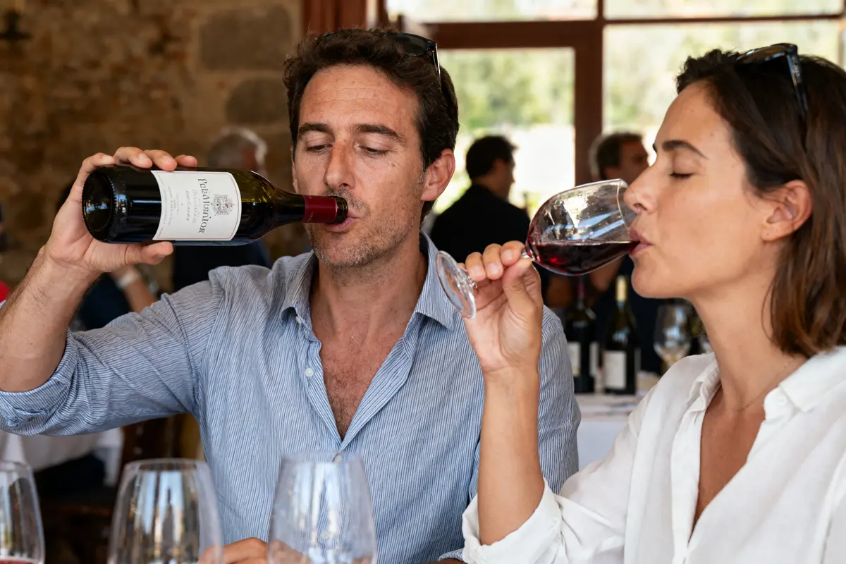 Deux personnes dégustent du vin rouge dans un restaurant, ambiance conviviale et décontractée.